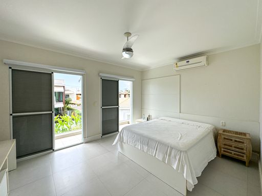 Suíte master com sacada privativa

Quarto de casal com cama box branca, ventilador de teto e amplas portas para sacada.

Este amplo e arejado quarto de casal dispõe de uma cama box vestida com lençóis brancos minimalistas, posicionada à frente de um painel de cabeceira planejado de cor branca texturizada. O teto possui acabamento em gesso com spots embutidos e um ventilador de teto centralizado. Duas grandes portas de correr de vidro dão acesso a uma varanda privativa com guarda-corpo metálico, oferecendo vista para o jardim externo e os arredores. O ambiente exala frescor, tranquilidade e conforto térmico.