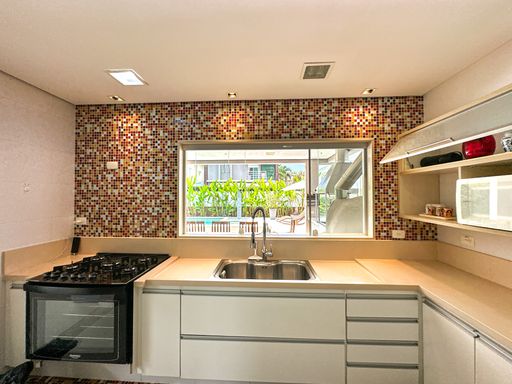 Bancada da pia da cozinha

Bancada de cozinha com cuba embutida, torneira gourmet sob janela de alumínio branco.

Uma perspectiva centralizada da área de lavagem da cozinha mostra a bancada de pedra bege polida instalada logo abaixo de uma ampla janela de correr de alumínio branco. O destaque visual continua sendo o mosaico de pastilhas coloridas, iluminado por spots embutidos no teto. A cuba de inox escovado possui uma torneira moderna e a marcenaria inferior em tom branco oferece gaveteiros organizados para utensílios. A atmosfera combina funcionalidade e estilo de forma equilibrada e iluminada.