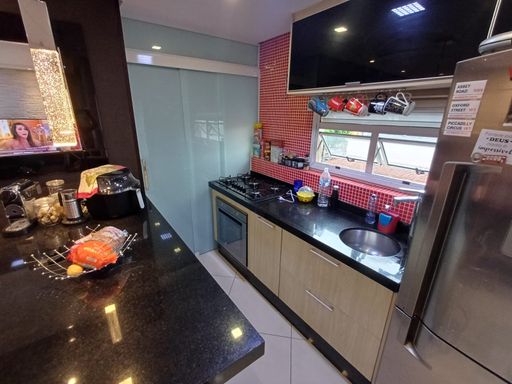 cozinha com armários planejados e ilha com acesso a área de serviço com porta de vidro em 3 partes trazendo mais espaço