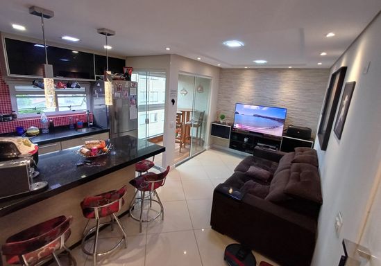 ampla sala semi integrada a sacada envidraçada e a cozinha padrão americana