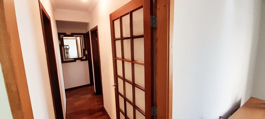 corredor de acesso aos dormitórios com porta em madeira e vidro, trazendo sofisticação ao ambiente