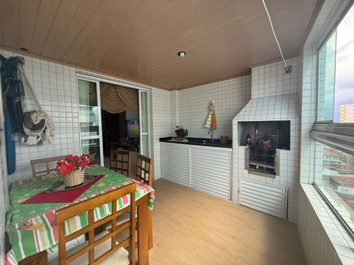 ampla varanda gourmet envidraçada com churrasqueira a carvão