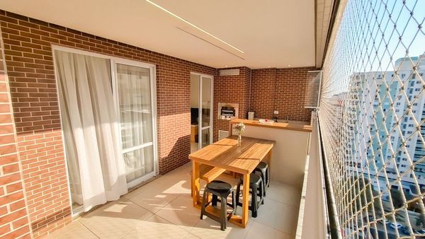 ampla varanda gourmet envidraçada com tela de proteção, churrasqueira, acesso a sala 2 ambientes e a área de serviço