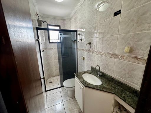 banheiro da suíte arejado com box de vidro e armário planejado