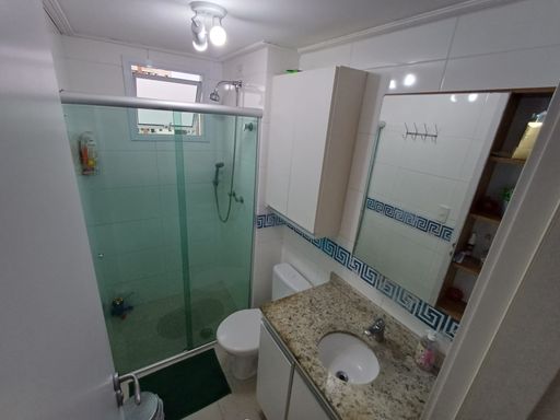 banheiro da suíte bem arejado com box blindex e armário planejado com pia em granito