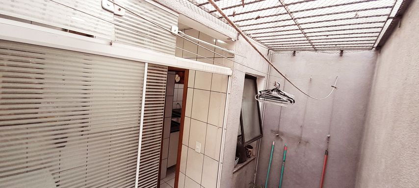 quintal com acesso a área de serviço com porta de correr de vidro e a cozinha