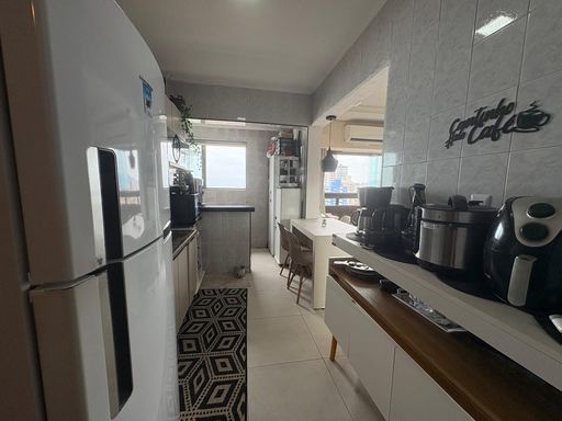 cozinha semi integrada a área de serviço bem arejada e a sala