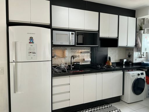 cozinha com móveis planejados com ampla pia em granito preto, semi integrada a área de serviço