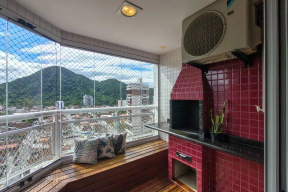 Varanda gourmet em formato de deck com churrasqueira a carvão e vista livre