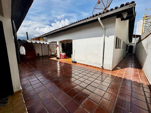 amplo quintal com churrasqueira a carvão e corredor de acesso a entrada principal