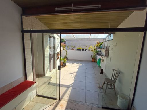 área externa na cobertura com porta de correr de vidro e extensão do telhado também envidraçado