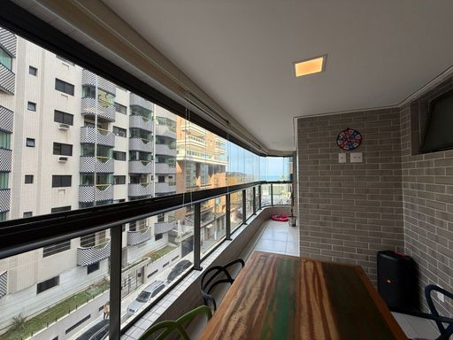 ampla varanda gourmet envidraçada com vista mar privilegiada, churrasqueira a carvão e cortina blackout
