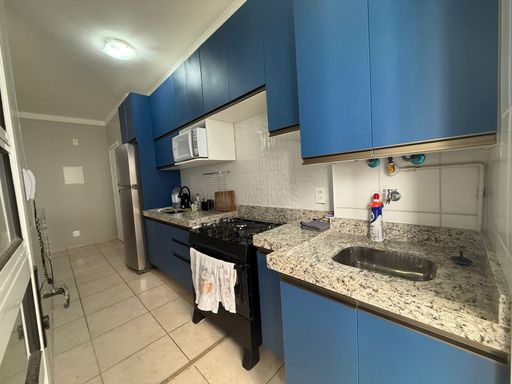 cozinha com armários planejados e pia ampla em granito, semi integrada a área de serviço com acesso a sacada