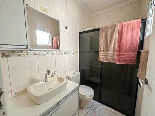 banheiro da suíte com box de vidro e armário planejado