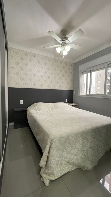 suíte com armário planejado, papel de parede em total harmonia, ampla janela estilo persiana blackout e ventilador de teto