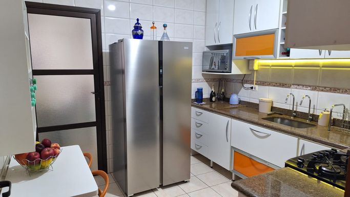 cozinha planejada com ampla pia em granito e porta de acesso de vidro para a área de serviço
