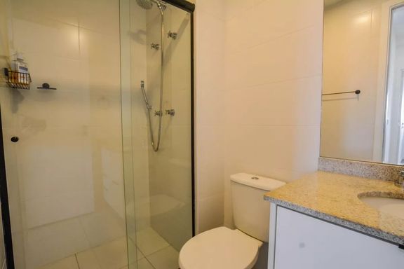 Banheiro social ultra moderno e espaçoso, com box de vidro e armário planejado