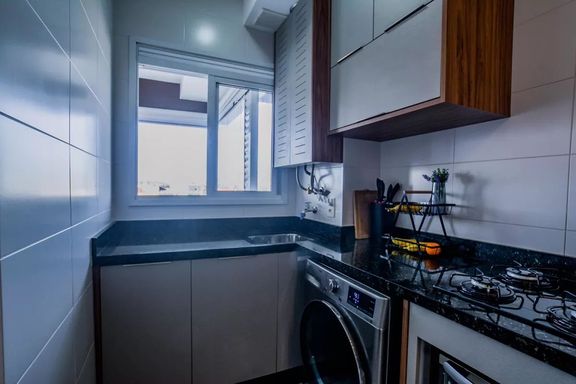 Área de serviço também com móveis planejados e pia em granito preta, bem arejada