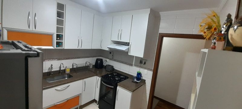 cozinha planejada com ampla pia em granito e acesso a entrada principal