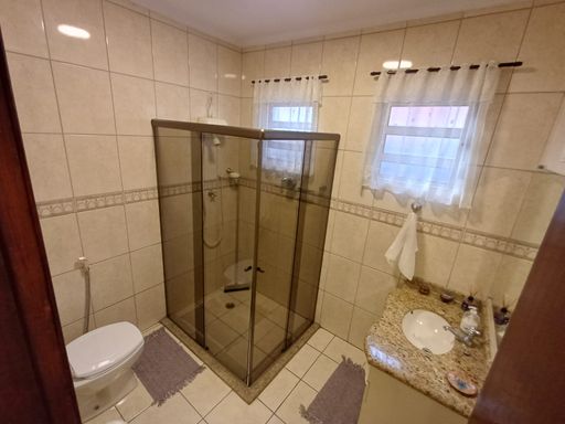 amplo banheiro social arejado com armário planejado e box de vidro