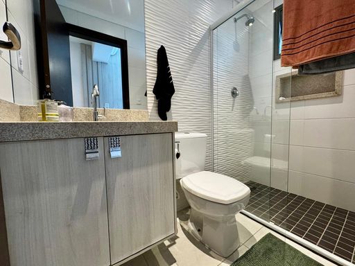 banheiro da suíte com armário planejado, nicho e box de vidro