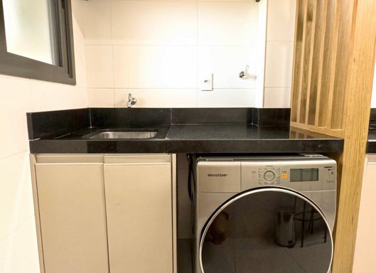 área de serviço arejada com móveis planejados e pia em granito preta