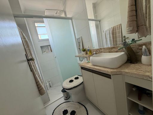 banheiro da suíte bem arejado com nicho, armário planejado e box de vidro