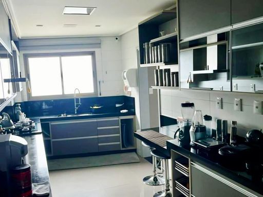 cozinha totalmente planejada e mobiliada com ampla pia em granito preta, semi integrada a área de serviço