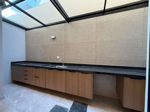 área gourmet externa retrátil com pia ampla e bancada em granito preta, com armários planejados, em total requinte