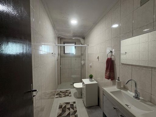 banheiro bem arejado com box de vidro e armário