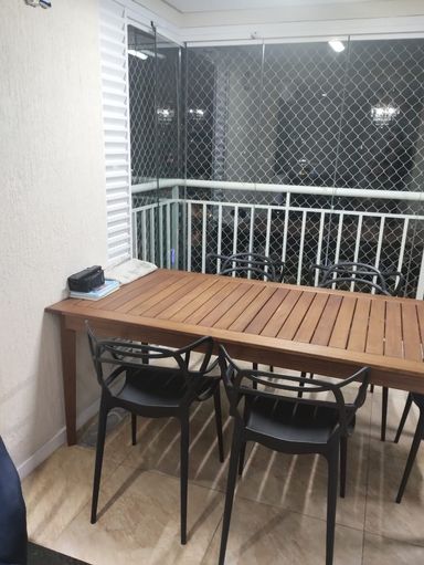 ampla varanda gourmet envidraçada com tela de proteção e churrasqueira a carvão