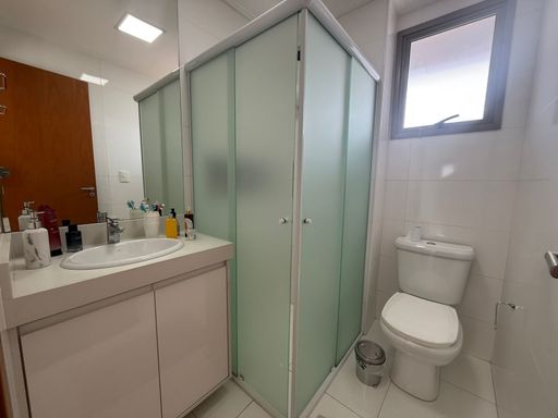 banheiro da suíte bem arejado com box de vidro e armário planejado