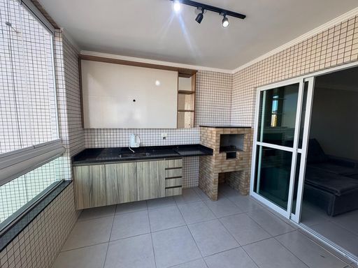 Ampla varanda gourmet envidraçada com churrasqueira a carvão, armário planejado e pia ampla em granito preta