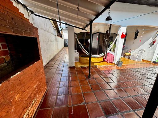 amplo quintal com churrasqueira a carvão e corredor de acesso a entrada principal