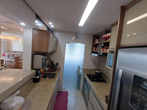 cozinha americana com armários planejados e acesso a área de serviço com porta de vidro