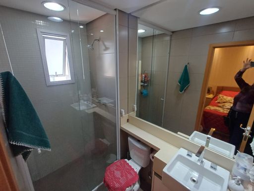 banheiro da suíte com armário planejado e box de vidro, bem arejado