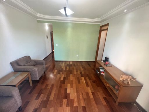 ampla sala com piso em madeira e acesso a entrada principal e aos dormitórios