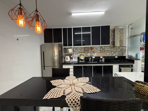 cozinha com armários planejados com balcão em granito preto, semi integrada a área de serviço com porta de correr de vidro