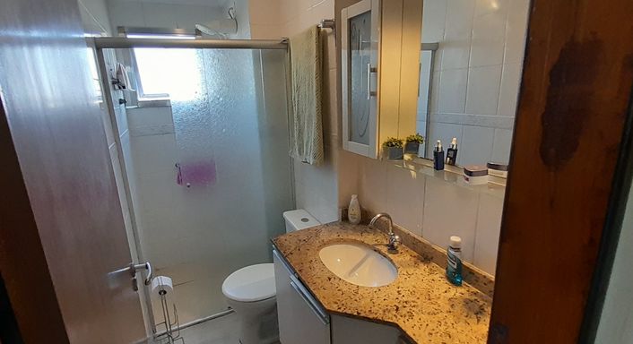 banheiro com box blindex e armário planejado com ventilação natural