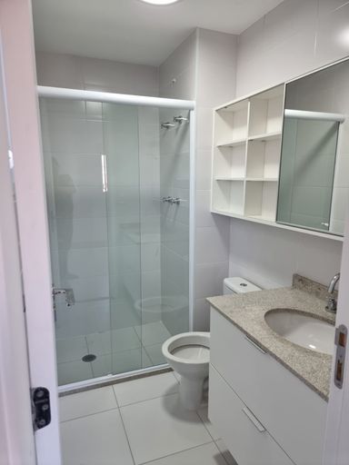 Banheiro da suíte com móveis planejados e box de vidro