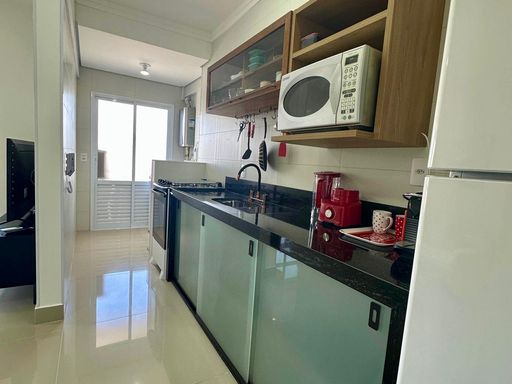 cozinha com ampla pia em granito preta semi integrada a área de serviço e área técnica