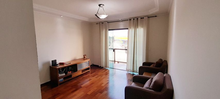 ampla sala com piso em madeira e acesso a sacada