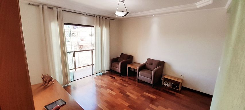 ampla sala com piso em madeira e acesso a sacada