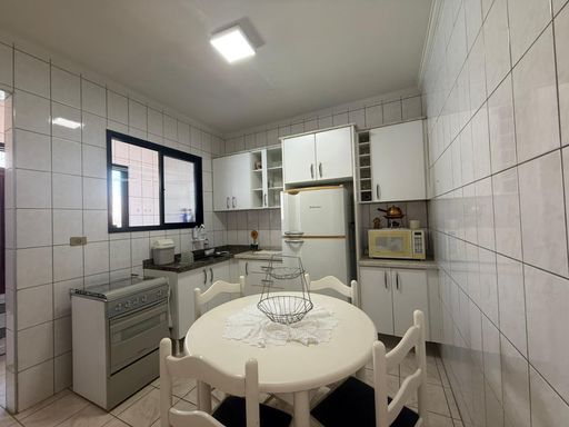 ampla cozinha arejada com armários planejados e acesso a área de serviço