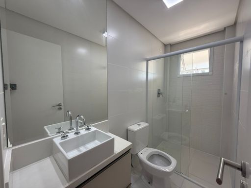 banheiro da suíte bem arejado, com box de vidro e armário planejado