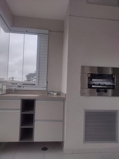 Ampla varanda gourmet envidraçada com churrasqueira e móvel planejado