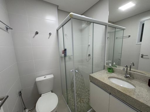 Banheiro da suíte bem arejado com armário planejado e box de vidro