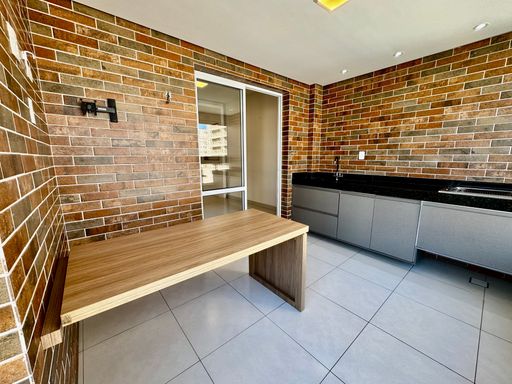 Ampla varanda gourmet envidraçada com churrasqueira e acesso a sala 2 ambientes