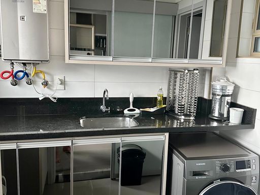 cozinha totalmente planejada e mobiliada com ampla pia em granito preta, semi integrada a área de serviço