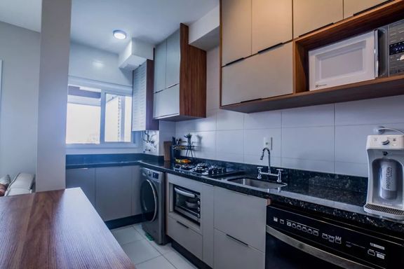 Ampla cozinha com móveis planejados, ampla pia em granito preta, semi integrada a área de serviço bem arejada